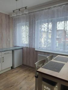 a kitchen with a table and chairs and windows at Hotel Schneider Apartaments in Langenhagen