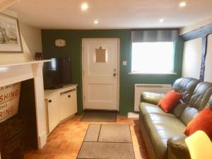 een woonkamer met een leren bank en een deur bij Bakers Cottage Ludham - Norfolk Broads in Ludham