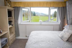 um quarto com uma cama e uma grande janela em The Cottage Tea Room B&B em Kettlewell