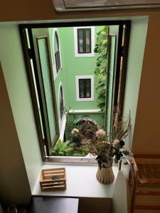 The Bambu Room at Casa of Essence located in heart of Old San Juan في سان خوان: نافذة بها إناء من الزهور على طاولة