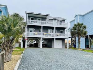 a large house with palm trees and a driveway at Beach Bells Home in Holden Beach
