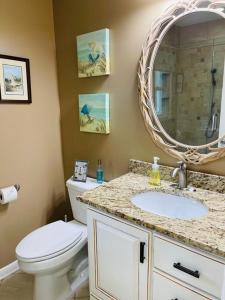 a bathroom with a toilet and a sink and a mirror at Beach Bells Home in Holden Beach