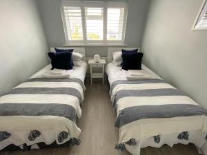 two twin beds in a small room with windows at Large family Bungalow, parking & Bike Store BPW in Merthyr Tydfil