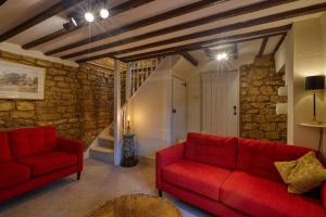 a living room with red couches and a stone wall at Fab 2 Bed Cotswolds Cottage with Private Courtyard 