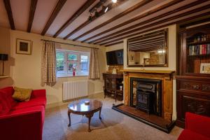 a living room with a red couch and a fireplace at Fab 2 Bed Cotswolds Cottage with Private Courtyard 