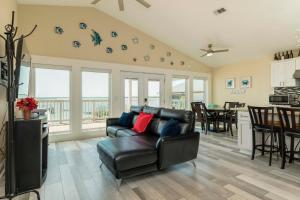 a living room with a black leather couch and a kitchen at On Galveston Bay Spacious Home with Pier and Grills! in San Leon