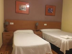 two beds in a room with white sheets at Nou Rocamar in Sant Carles de la Ràpita