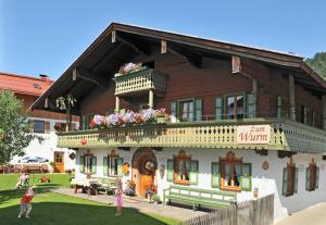 - un grand bâtiment en bois avec des fleurs sur le balcon dans l'établissement Gästehaus Zum Wurm, à Reit im Winkl
