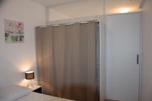 - une chambre avec un rideau de douche et un lit dans l'établissement Les terrasses de Mirande, à La Rochelle