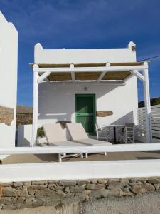 a white house with a green door and two chairs at Romantic loft 2 in Ios Chora