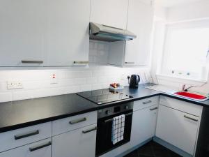 a kitchen with white cabinets and a stove top oven at Beautiful 3 Bedroom Apt, mins from Glasgow Airport, M8 & SEC in Paisley