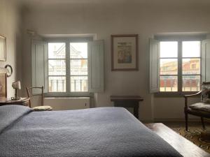 a bedroom with two windows and a bed and a chair at ATTICO IN PIAZZA SANTA CROCE in Florence