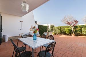 - une table avec des chaises et un vase de fleurs sur la terrasse dans l'établissement White Sea Villas by Wonderful Italy, à Carovigno