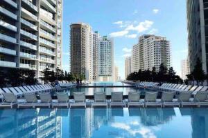a swimming pool with white chairs and buildings at Icon Brickell -LUX 2 Bedroom with City & Bayview in Miami