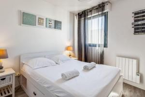 een slaapkamer met een wit bed en 2 handdoeken bij Nice flat with terrace & parking close to beaches in La Rochelle - Welkeys in La Rochelle