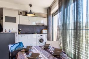 a kitchen with a dining table with chairs and a window at Nice flat with terrace & parking close to beaches in La Rochelle - Welkeys in La Rochelle