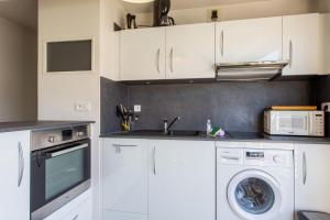 a kitchen with white cabinets and a washer and dryer at Appartement Goélette - Welkeys in La Rochelle