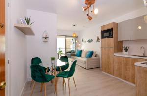 a kitchen and living room with a table and green chairs at Maestranza Beach by Sol Maestranza in Málaga