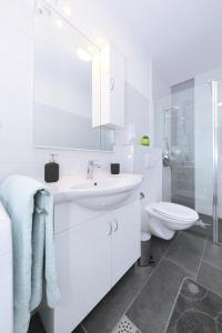 a white bathroom with a sink and a toilet at Apartman Lili in Zadar