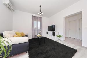 a white living room with a couch and a tv at Apartman Lili in Zadar