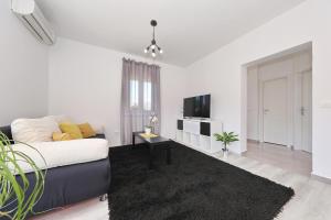 Una sala de estar blanca con un sofá y un televisor. en Apartman Lili, en Zadar