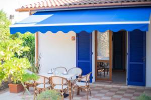 a patio with a table and chairs under a blue awning at Villa le Palme in Capoliveri