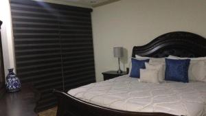 1 dormitorio con 1 cama grande con almohadas azules y blancas en ESMERALDA B-201, en Puerto Peñasco