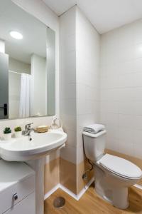 a white bathroom with a toilet and a sink at Micampus Bormujos in Bormujos