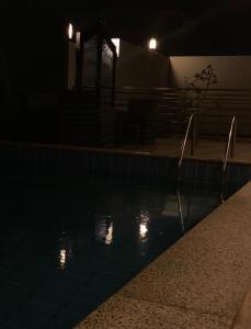 una piscina por la noche con luces en el agua en Open ApartHotel, en Dammam