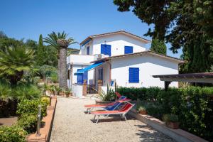 una casa con persianas azules y dos sillas en un patio en Villa le Palme, en Capoliveri