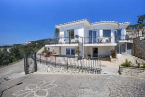 a large white villa with a fence in front of it at Amore Rentals - Villa Ligea in SantʼAgata sui Due Golfi