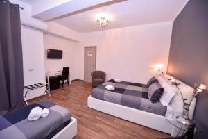 una camera d'albergo con due letti e una scrivania di Symposium Bed&Breakfast a Catania