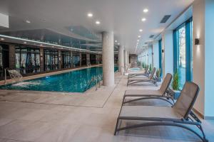 a pool in a building with chairs and a swimming pool at Apartament Sedina D211 Nadmorskie Tarasy in Kołobrzeg