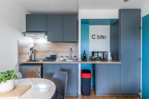 a small kitchen with blue cabinets and a table at Nice flat 150m to the beach in Villers-sur-Mer - Welkeys in Villers-sur-Mer