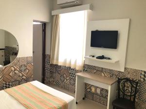 a bedroom with a bed and a tv on a wall at Aldeota Praia Hotel in Fortaleza