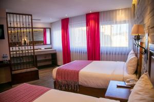 a hotel room with two beds and red curtains at Hotel Alameda Centro Historico in Morelia