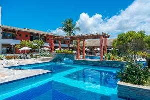 a swimming pool in front of a hotel at Porto das Naus Praia Hotel in Porto Seguro