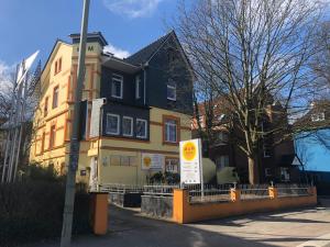 a yellow house with a sign in front of it at M&M Hotel - Harburg in Hamburg