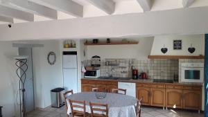 una cocina con armarios de madera y una mesa con sillas. en Gîte La Fortaiserie, en Rillé