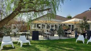 a group of white chairs and tables in a yard at Best Western Hotel Acadie Paris Nord Villepinte in Tremblay-En-France