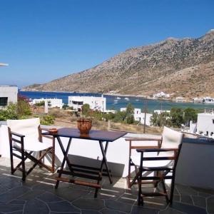 a table and chairs on a patio with a view at KIRIKOS ROOMS in Sifnos