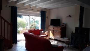 sala de estar con sofá, TV y ventana en Gîte La Fortaiserie, en Rillé