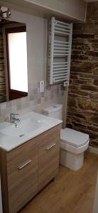 a bathroom with a sink and a toilet and a window at Apartamentos Fons sacrata in Fonsagrada