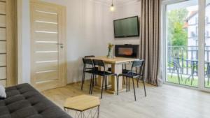 ein Wohnzimmer mit einem Tisch und Stühlen sowie einem TV in der Unterkunft Apartament San in Łeba