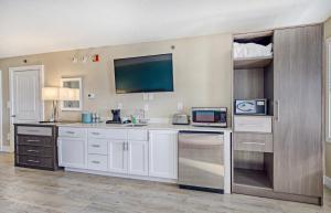 a kitchen with white cabinets and a tv on the wall at Commander Hotel & Suites in Ocean City
