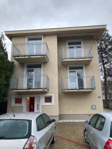 two cars parked in front of a building with balconies at Vila ViV Srebrno Jezero in Veliko Gradište