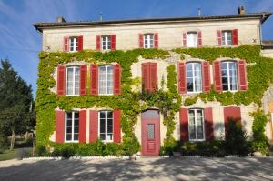 een groot huis met rode deuren en klimop bij Suite parentale de luxe in Rouffignac