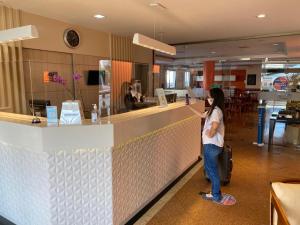 a woman standing at a counter in a restaurant at Champagnat Praia Hotel in Vila Velha