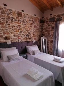 two beds in a room with a stone wall at Castro Rooms Chios in Chios