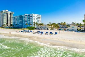 a beach with beach chairs and buildings and the ocean at Grand Shores West in St Pete Beach